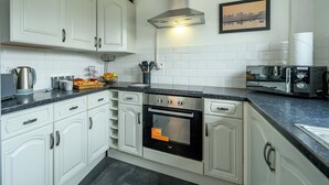 A kitchen with white cabinets, a stainless steel oven, a microwave, and a coffee maker. - 2 Bed home, close to the hospital and town centre - Pass the Keys (Shrewsbury)