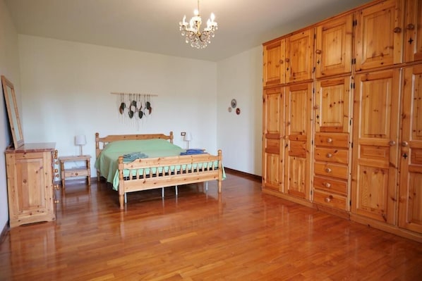 Un dormitorio con una cama y un armario de madera, y una araña.