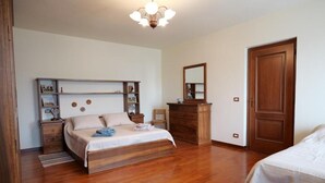 Ein Schlafzimmer mit einem hölzernen Bett, einem Schminktisch, einem Spiegel und einem Regal mit Fotos.