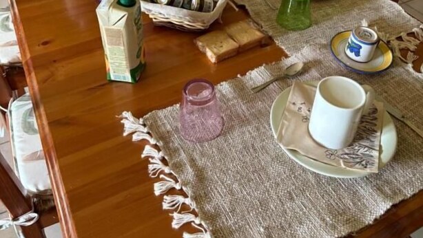 Ein Holztisch ist reichhaltig mit verschiedenen Gegenständen gedeckt, darunter eine Blumenvase, ein Korb, Gläser und eine Krug.