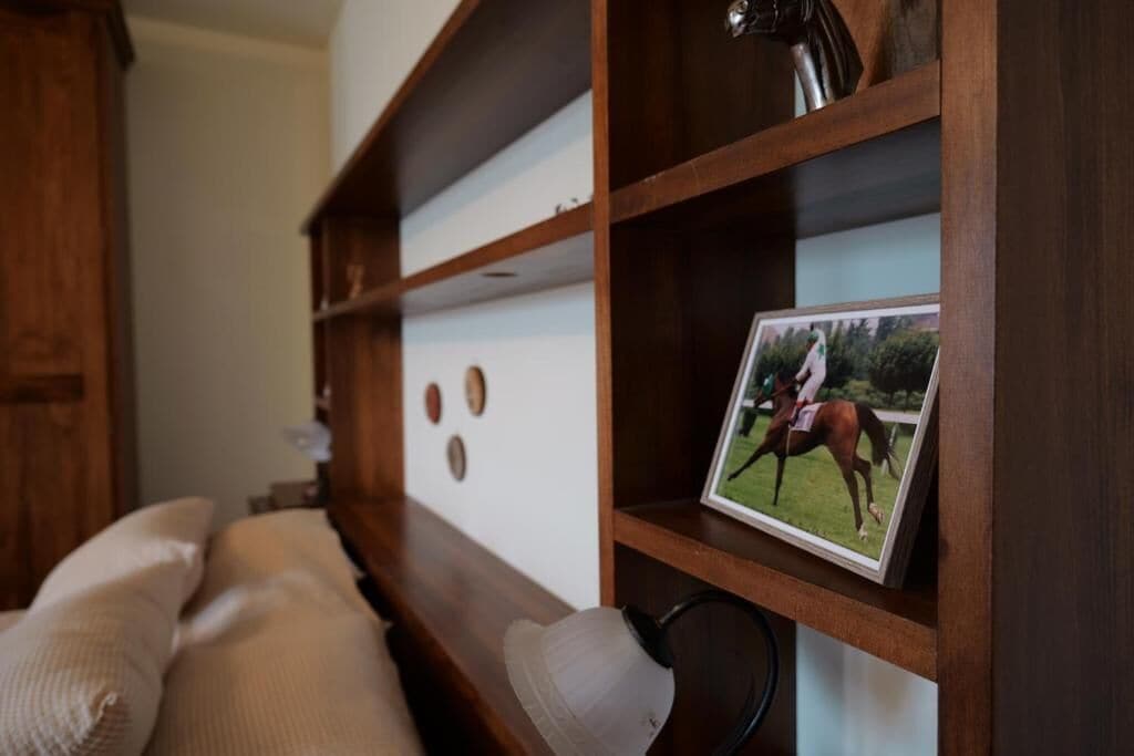 Ein Bücherregal aus Holz mit einem gerahmten Foto von einer Person zu Pferd.