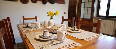 A dining table set with plates, cups, and a vase of yellow flowers.