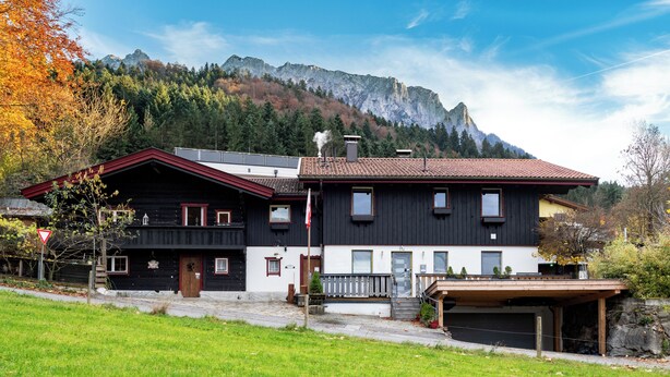 A two-story house with a garage, a front porch, and a mountain backdrop. - Room-charming Guest Room in Ebbs Nature (Ebbs)