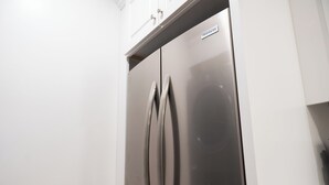 Ett kylskåp i rostfritt stål med en etikett som visar varumärket ”FRIGIDAIRE”, vita skåpluckor och en liten hylla ovanför dörren.