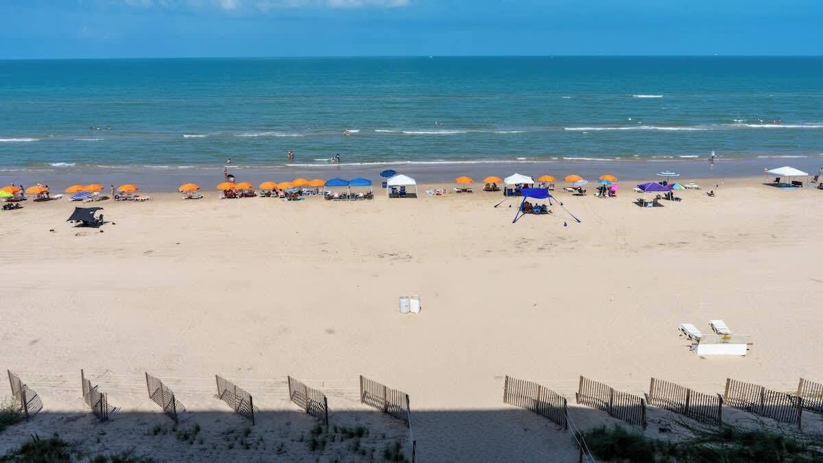 A beach with umbrellas, sun loungers, and a sandy shore.