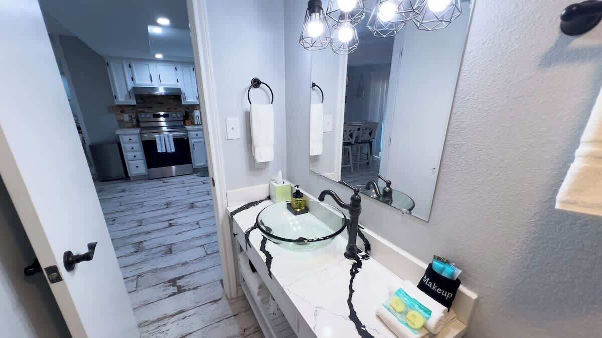 A bathroom with a glass sink, white cabinets, and a large mirror.