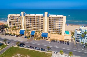 A multi-story hotel with a beach view, parking lot, and a road in the foreground.