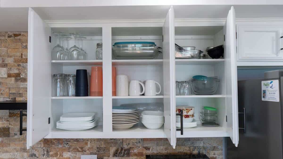 A kitchen with open cabinets displaying glassware, plates, and bowls.
