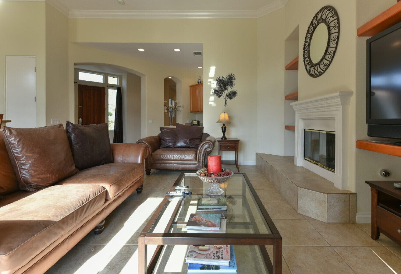 Una sala de estar con un sofá de cuero, una mesa de centro de vidrio, una chimenea y un televisor.