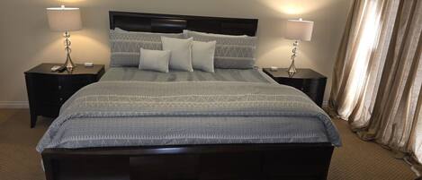 A bedroom with a large bed, two bedside tables, and a headboard.