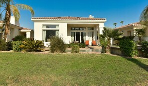 Ein zweistöckiges Haus mit Ziegeldach, einer Veranda mit Stühlen und einem Swimmingpool.
