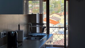 A kitchen with a kettle, a sink, and a window overlooking a residential area.