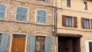 A stone building with wooden shutters, a wooden door, and a garage entrance.