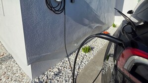 Una estación de carga para vehículos eléctricos adosada a la pared exterior de un edificio.