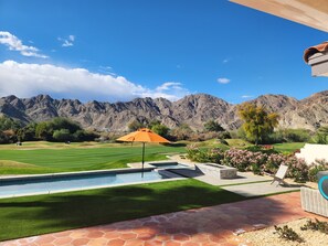 Ein Poolbereich mit Blick auf Berge, einen Golfplatz und eine Terrasse mit Sitzgelegenheiten.