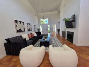 Ein modernes Wohnzimmer mit einem schwarzen Ecksofa, weißen Sessel, einem Couchtisch und einem Kamin.