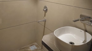 A modern bathroom with a white sink, a shower area, and a ceiling light.