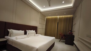 A modern hotel room with a large bed, a desk, a chair, and a ceiling fan.