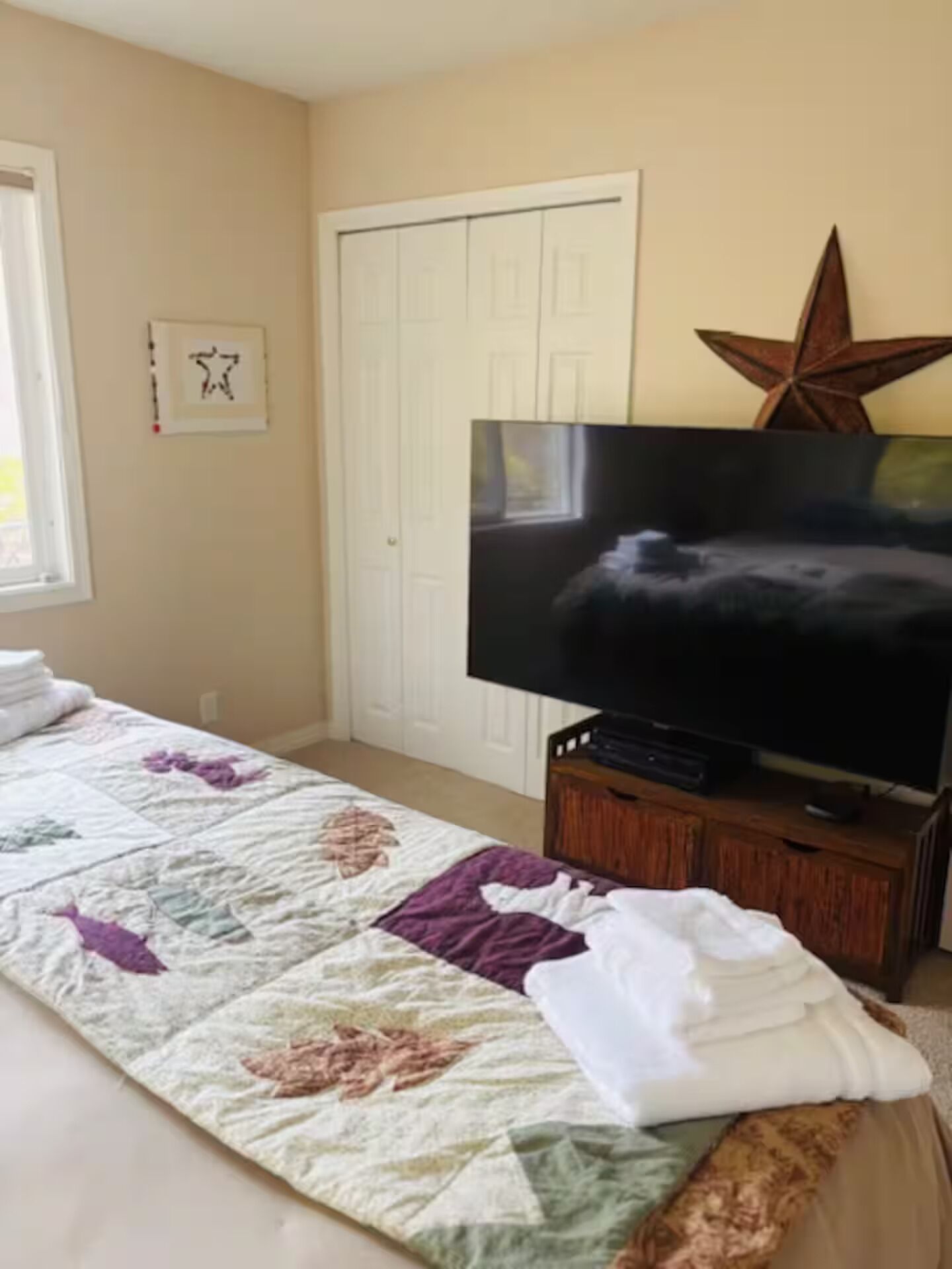 Ein Schlafzimmer mit einem Bett, einem Fernseher auf einem Holzboden, einer Sternen-Dekoration und einer Tür.