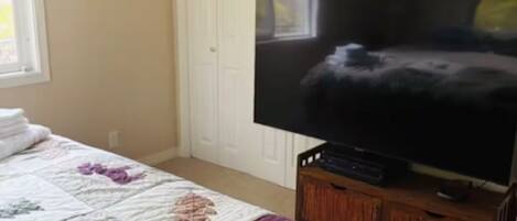 Ein Schlafzimmer mit einem Bett, einem Fernseher auf einem Holzboden, einer Sternen-Dekoration und einer Tür.