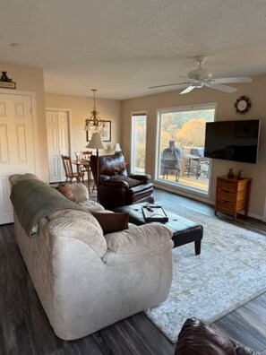 A living room with a sofa, a television, and a dining area with chairs and a table.