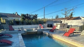 Ein Schwimmbecken mit Stufen, umgeben von Liegestühlen und einer Steindeckterrasse.