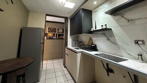 Eine kompakte Küche mit Kühlschrank, Spüle, Herd und einem Essbereich mit Tisch.