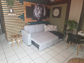 A modern living room with a grey sofa, a round wooden table, a wall clock, and a potted plant. - Bon Homme's / Private space in Cabo Rojo, full equipped / Near Beaches (Cabo Rojo)