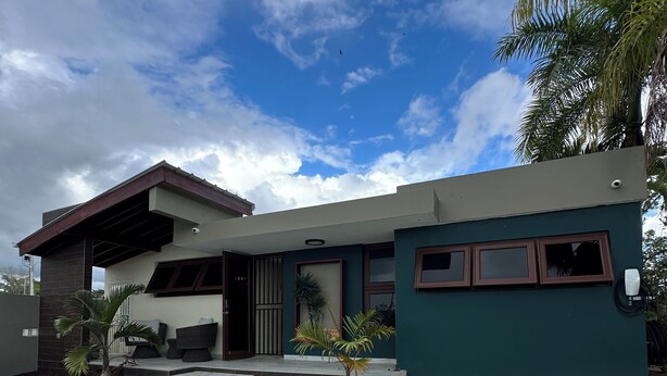 Ein modernes Haus mit überdachter Terrasse, gepflegtem Rasen und blauem Himmel.