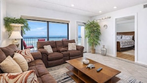 Ein modernes Wohnzimmer mit Sofa, Couchtisch und Meerblick.