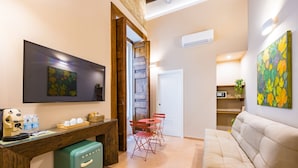 A modern living room with a sofa, a coffee table, a TV, and a staircase leading to another room. - BORGO VERGINI SUITES (Naples)