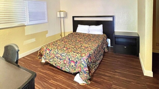 A hotel room with a bed, a desk, a chair, a lamp, and a window. - Cloud 9 Motel Cypress Buena Park (Cypress)