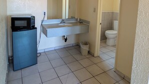 A bathroom with a sink, mirror, toilet, and a microwave. - Cloud 9 Motel Cypress Buena Park (Cypress)