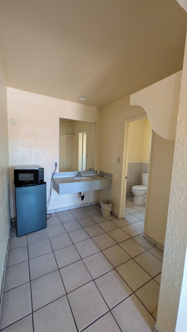A bathroom with a sink, mirror, toilet, and a microwave. - Cloud 9 Motel Cypress Buena Park (Cypress)
