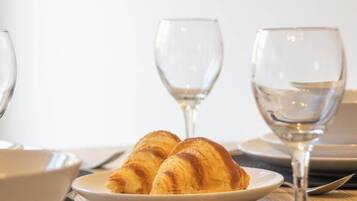 A plate with croissants and two empty wine glasses on a table.