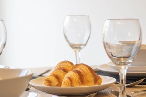 A plate with croissants and two empty wine glasses on a table. - Modern 2BR Home in Grantham | King Bed | Sleeps 4 (Lincolnshire)