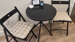Una pequeña mesa redonda con dos sillas, una pared blanca y un suelo de madera.