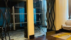 A conference room with glass doors, a chair, and a patterned rug. - Modern City Escape at Forbeswood Parklane (Taguig City)