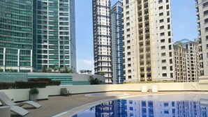 A swimming pool with a 4 FT depth marker, surrounded by modern high-rise buildings. - Modern City Escape at Forbeswood Parklane (Taguig City)