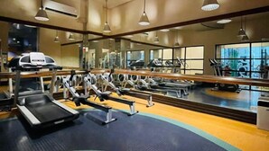 A gym with treadmills, weight machines, and mirrors. - Modern City Escape at Forbeswood Parklane (Taguig City)