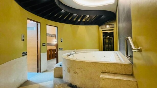 A modern interior with a curved staircase leading to a spa area, including a hot tub and a wooden door. - Comfort & Convenience at Forbeswood Parklane (Taguig City)
