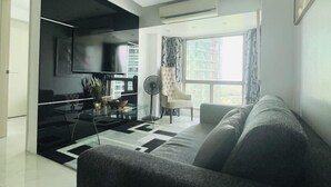 Una sala de estar moderna con un sofá, televisor y un comedor con mesa y sillas.