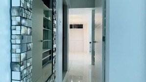 Un pasillo con pared de azulejos, puerta de cristal y suelo limpio y brillante.