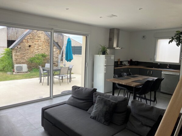A modern kitchen with a dining area, a sofa with cushions, and a view of the outside.
