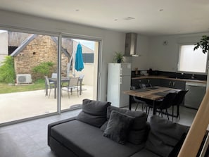 Une cuisine moderne avec un coin repas, un canapé avec des coussins et une vue sur l’extérieur.