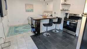 Une cuisine compacte dotée d’appareils électroménagers modernes, un coin repas avec une table et des chaises, et un petit coin salon agrémenté d’un tapis.