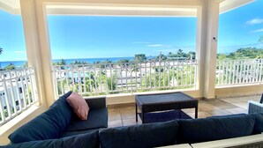 A balcony with a view of the ocean, a white railing, and a black sofa with cushions. - Private Home Pool Ocean Views Walk to Beach (Rincon)