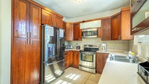 A kitchen with wooden cabinets, stainless steel appliances, and a tiled backsplash. - Private Home Pool Ocean Views Walk to Beach (Rincon)