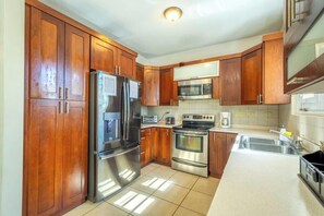 A kitchen with wooden cabinets, stainless steel appliances, and a tiled backsplash.
