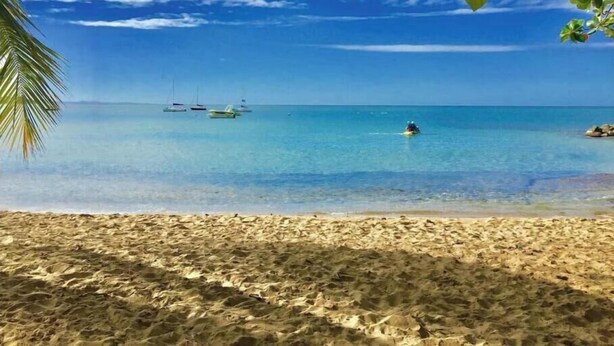 A beach with clear water, boats, and a person on a jet ski. - Private Home Pool Ocean Views Walk to Beach (Rincon)